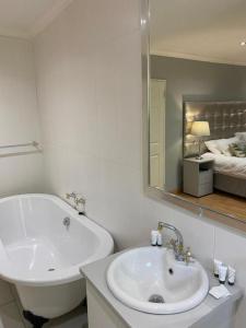 a bathroom with a sink and a tub and a mirror at Boutique at milner guesthouse in Bloemfontein