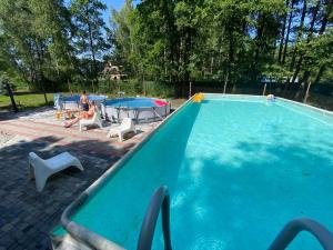 a man sitting in a chair next to a swimming pool at Apartament Nad Stawem in Wadowice
