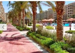 Un paseo con palmeras y una piscina. en Aqua view resort studio, en El Qasaba esh Sharqīya
