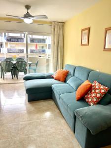 a living room with a blue couch with orange pillows at NOVA PINEDA 2 y VISTAS PISCINA in La Pineda