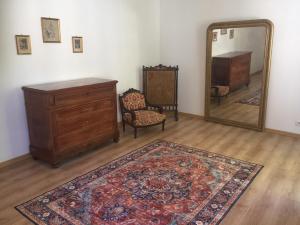 una stanza con una cassettiera, uno specchio e un tappeto di Logement Château de Villeneuve  1 altra foto