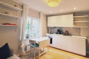 cocina con armarios blancos, mesa y ventana en Flat in Telliskivi area, en Tallin