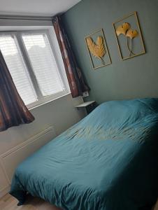 a bedroom with a blue bed and two windows at Grand studio centre-ville in Villedieu-les-Poëles
