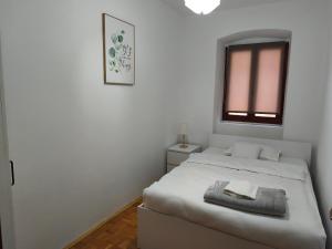 a white bedroom with a bed and a mirror at Apartman Nina Vrlika in Vrlika