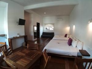 a bedroom with two beds and a table and a television at Hotel Rockaway in Puerto Escondido