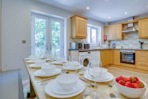 une cuisine avec une longue table avec des assiettes blanches et des verres à vin dans l'établissement Spacious & Stylish 5BR Townhouse - Free Parking, à Manor