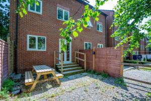 une maison avec une clôture et un banc en bois dans l'établissement Spacious & Stylish 5BR Townhouse - Free Parking, à Manor