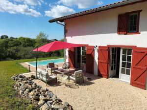 a patio with a table and an umbrella next to a house at Maison basque de charme avec piscine in Souraïde