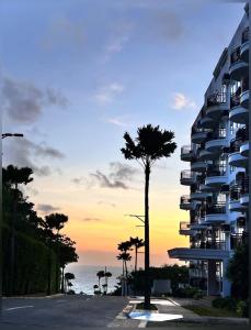 a palm tree in front of a building with the ocean at Sharon's Island - Newcoast Boracay in Boracay
