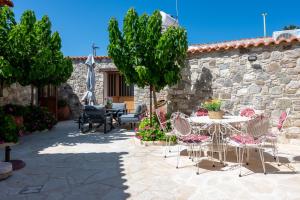 a patio with tables and chairs and a stone wall at Terra Nobile, 3BR Mountain Stone Escape BBQ Fireplace in Galataria