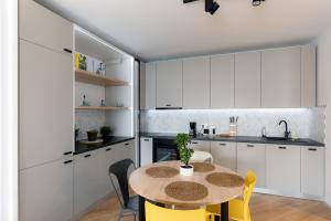 a kitchen with white cabinets and a table and chairs at City One I One Bedroom Apartment near Pipera Plaza Mall in Voluntari