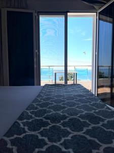 a bedroom with a bed with a view of the ocean at Manas Rooms in Dhërmi