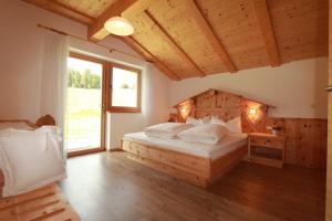 a bedroom with a large bed with a wooden headboard at Apartments DAMONT in Santa Cristina Gherdëina
