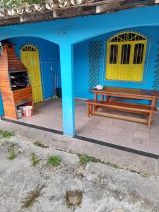 a blue building with a bench and a yellow door at Casa de praia Aninha in Belém