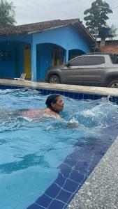 a man is swimming in a swimming pool at Casa de praia Aninha in Belém +1 photo