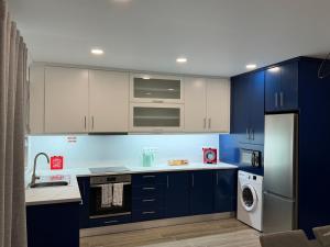 a kitchen with blue cabinets and a washer and dryer at Ponto de vista in Angra do Heroísmo