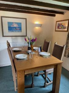 einen Holztisch mit Stühlen, Teller und Blumen darauf in der Unterkunft South Sandpark Cottage in Barnstaple + 11 Fotos