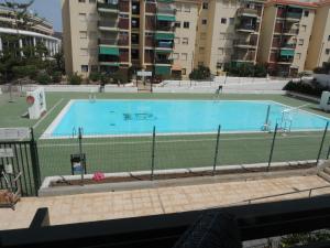 a swimming pool with a tennis court and a tennis net at Accessible Cristimar in Los Cristianos