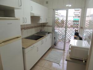 a kitchen with white cabinets and a door to a patio at Accessible Cristimar in Los Cristianos
