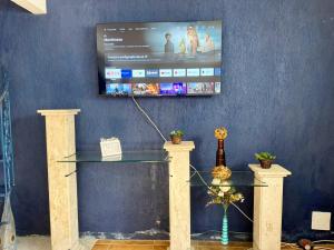 une table en verre avec une télévision sur un mur dans l'établissement Casa Espaçosa 6 Qts Churrasqueira 10 min Praia do Forte, à Cabo Frio 40 autres photos