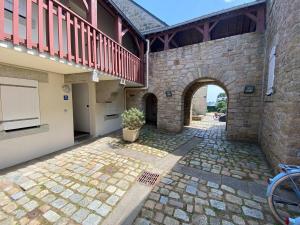 an archway in a brick building with a potted plant at Charmant appartement, proche mer avec piscine pour 4 personnes in Arzon