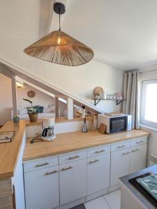 una cucina con mobili bianchi e un forno a microonde di Studio 3 couchages vue mer a Châtelaillon-Plage Altre 7 foto