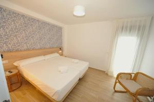 a bedroom with a white bed and a chair at Orange Park Duplex Atico Premium in Benicàssim +34 photos