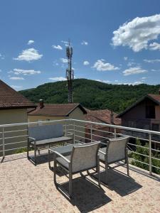 twee stoelen en een tafel op een patio met bergen bij Vila Dunjić Prolom Banja in Prolomska Banja
