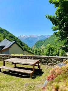 a wooden bench sitting in the grass with mountains in the background at Studio Bareges Le Rioulet 1 in Barèges