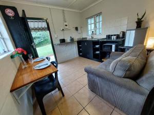 una sala de estar con un sofá y una mesa en Hill Top Cottage, en Pietermaritzburg 19 fotos más