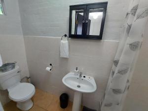 Un baño blanco con inodoro y lavabo. en Hill Top Cottage, en Pietermaritzburg