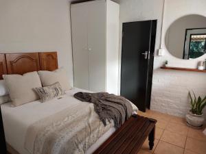 Un dormitorio con una cama y un banco de madera. en Hill Top Cottage, en Pietermaritzburg