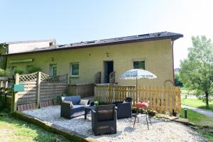 a house with a patio with chairs and an umbrella at Cocon au calme vue étang idéal familles et pros in Épinal