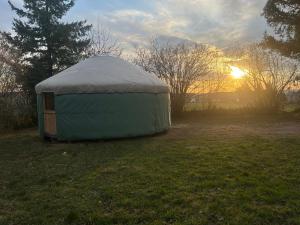 a yurt in a field with the sunset in the background at Gite Le Mas Rigal in Saint-Amans-des-Cots