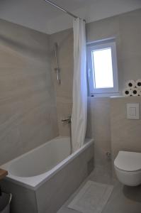 a bathroom with a tub and a toilet and a window at Apartments Gabriela in Drasnice