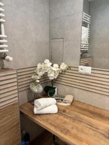 a bathroom with a counter with towels and a vase of flowers at Apartament Cesarski Agnes z oddzielną sypialnią, parking in Świnoujście +45 photos