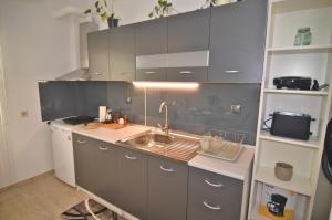Una cocina con gabinetes grises y un fregadero. en Azure, en Kastoria