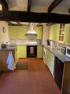 eine Küche mit hellgrünen Schränken und Fliesenboden in der Unterkunft South Sandpark Cottage in Barnstaple