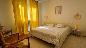 a bedroom with a bed and a window with yellow curtains at Maison Anatole France in Cahors