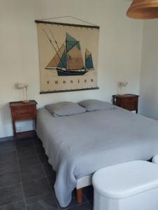 a bedroom with a white bed with a painting of a ship at Pampounette in Saint-Brévin-lʼOcéan