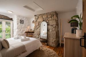 a bedroom with a large bed and a stone wall at Idyllic hideaway with hot tub, gym & gamesroom in Penzance
