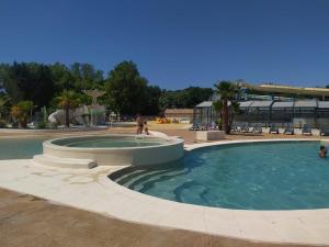 a pool in a park with people walking around it at Vacances dans les Landes in Aureilhan