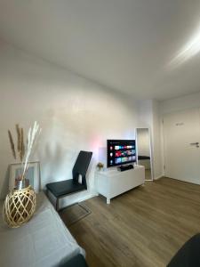a living room with a television and a chair at Modernes 1-Zimmer Appartment- mit Doppelbett und Smart-TV in Bonn