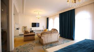 a bedroom with a living room with a couch and a tv at Grand Hotel Belushi in Boge