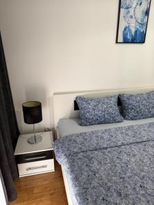 a bedroom with two beds and a lamp on a night stand at R&G apartman in Bijeljina