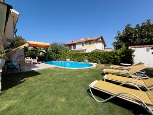a yard with lounge chairs and a swimming pool at Villa Fontes in Çeşme