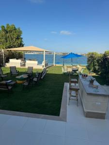a patio with tables and chairs and the water at فيلا فاخرة بشاطئ خاص وإطلالة ساحرة على البحيرة in El Alamein