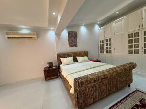 a bedroom with a large bed with a wicker couch at فيلا فاخرة بشاطئ خاص وإطلالة ساحرة على البحيرة in El Alamein