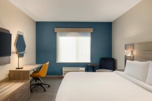 a hotel room with a bed and a desk and a window at Holiday Inn Express Fort Lauderdale Airport South by IHG in Dania Beach