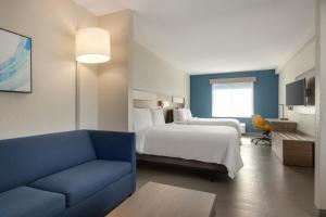 a hotel room with a bed and a blue couch at Holiday Inn Express Fort Lauderdale Airport South by IHG in Dania Beach